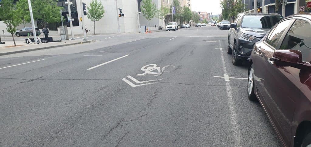 Faded "Sharrows" symbol on pavement along Wall St in Spokane. Reminds drivers that they must share the lanes with bicyclists.