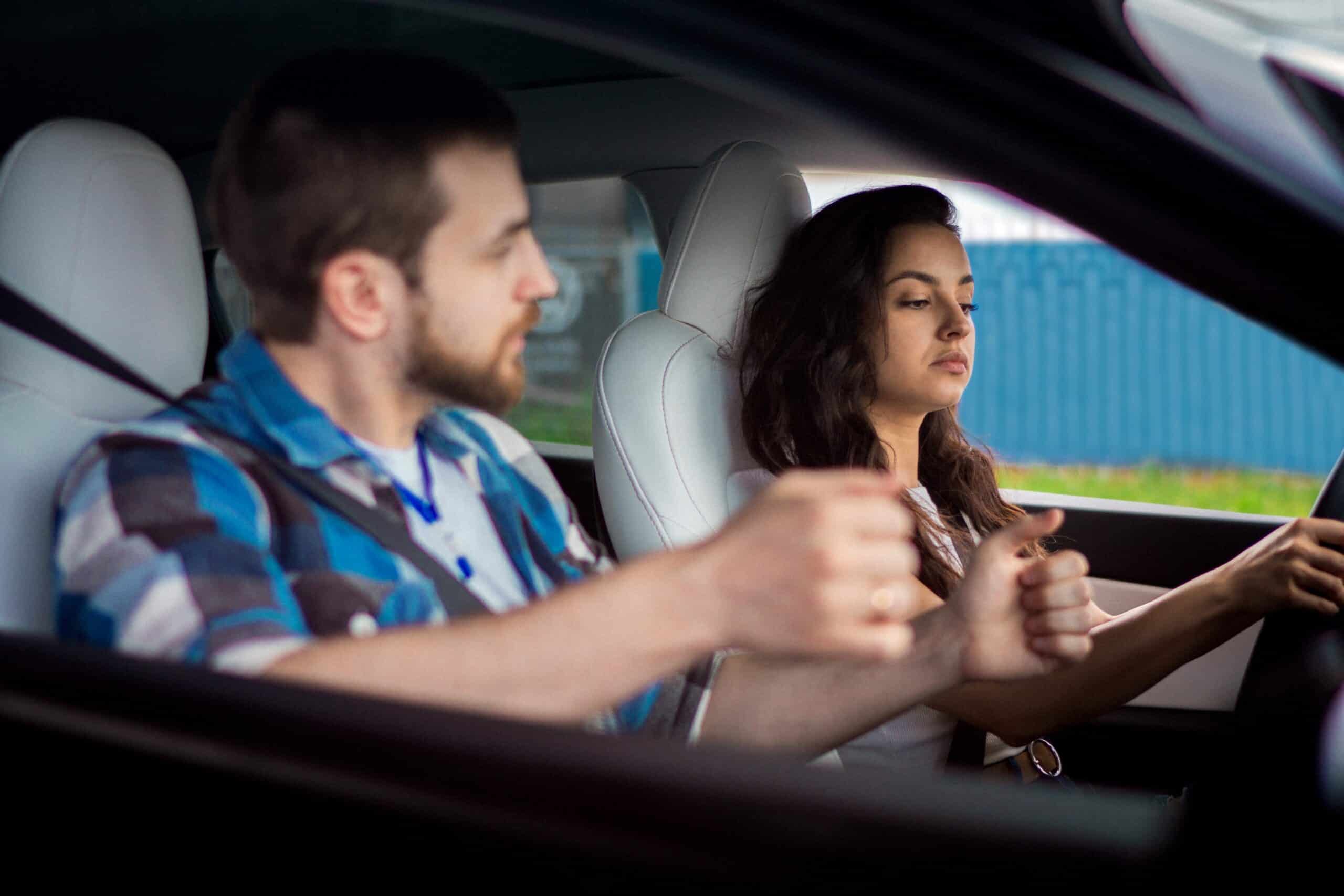 Driving school instructor teaching young driver behind the wheel
